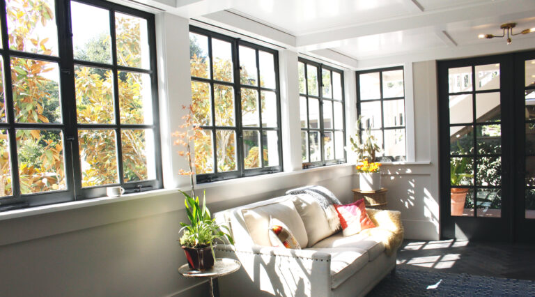 Large windows letting in bright sunshine on a white couch